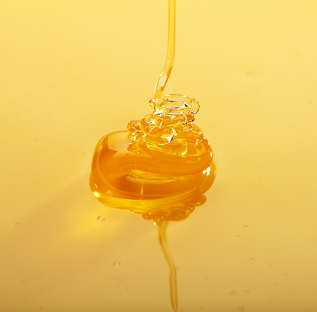 Macro of thick honey trickle pouring on honey surfaceの写真素材