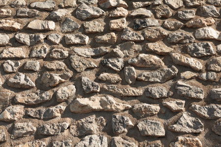 Fragment of wall made of grey stones in concrete as background