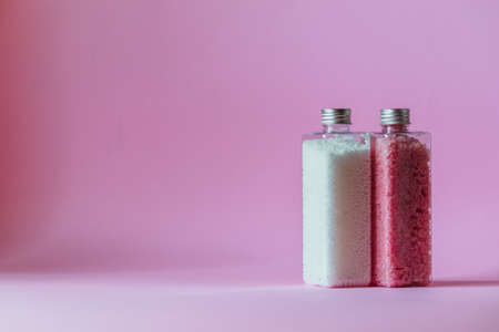 Bath shimmer and bath beads stand in transparent bottles on a pink background with empty space.の写真素材
