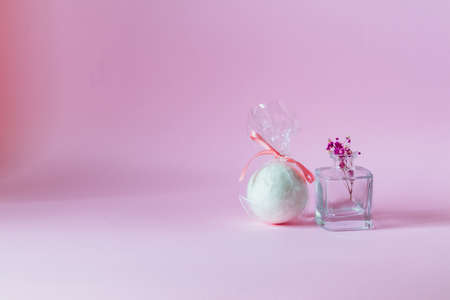 White bath bomb next to a small vase with flower on a pink background.の写真素材
