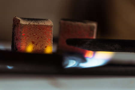 Coconut hookah coals stand on a gas stove and heat up at home or in a hookah bar.の写真素材