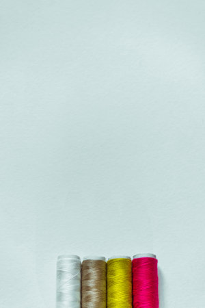 Vertical white background with four skeins of thread of different colors.