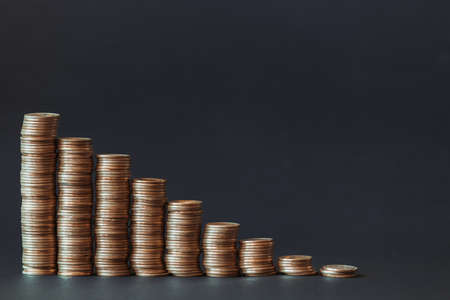 Falling graph in the form of gold coins on a black background.の写真素材