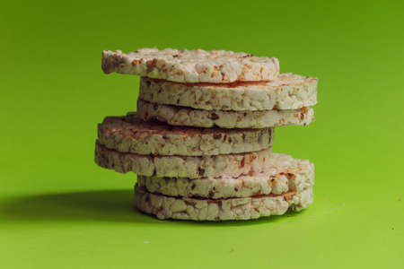 Seven round healthy breads stand in a column against a bright green background.の写真素材