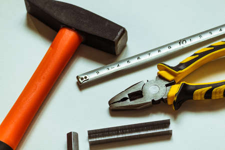 A set of metal hex keys next to a hammer, pliers and a tape measure on a white background.の写真素材