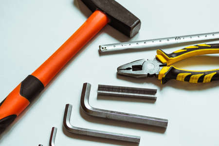 A set of metal hex keys next to a hammer, pliers and a tape measure on a white background.の写真素材