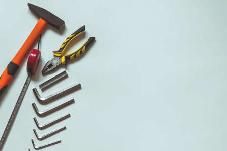 A set of metal hex keys next to a hammer, pliers and a tape measure on a white background with plenty of space for insertion.の写真素材