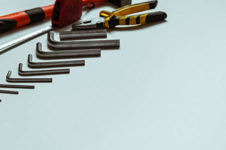 A set of metal hex keys next to a hammer, pliers and a tape measure on a white background.の写真素材