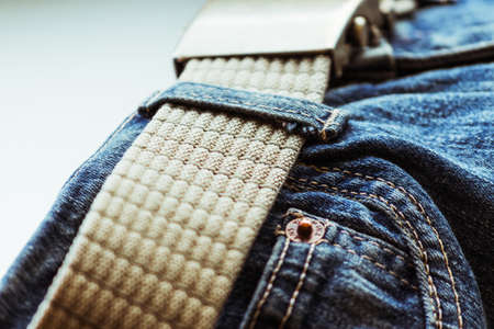 Blue jeans with a beige military nylon belt.の写真素材