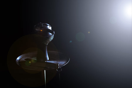 Hookah stands on a black background and a glare from the light shines on him.
