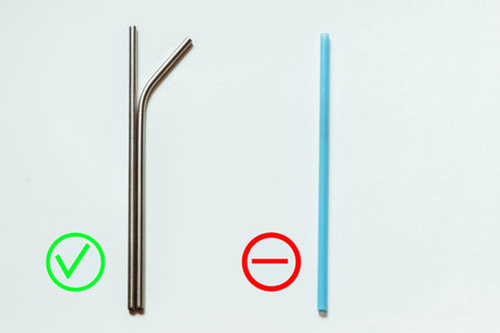 Reusable metal straws for drinks and disposable blue plastic straws lie on a white background....
