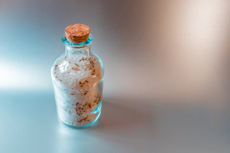 A large closed glass container with sea white salt stands against a light kitchen background.の写真素材