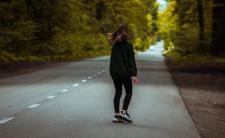 A girl walking in the middle of a forest trail.