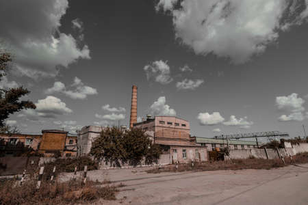 Gloomy old bricGloomy old brick factory with a chimney against a gray sky during the day.k factory with a chimney against a gray sky during the day. High quality photoの写真素材