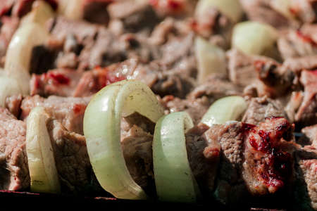 Pork kebab with onions on skewers close up. Barbecue cooking on the street. High quality photoの写真素材