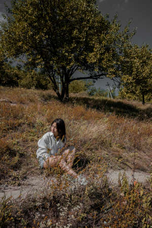 A girl in a white shirt, denim shorts and white sneakers lies on the lawn in warm weather. High quality photoの写真素材