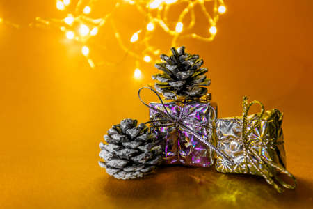 Gifts for the New Year. Small gifts small cones stand on a yellow background with lights and highlights. New Years atmosphere. High quality photoの写真素材