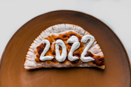 The number 2022 is written with sour cream on a cheburek. New year 2022 is coming soon. High quality photoの写真素材