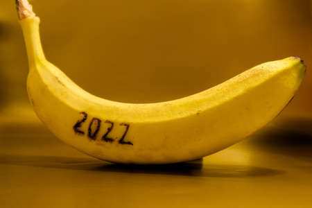 Numeral 2022 on a ripe yellow banana against a gold background. Preparing for the new year. High quality photoの写真素材