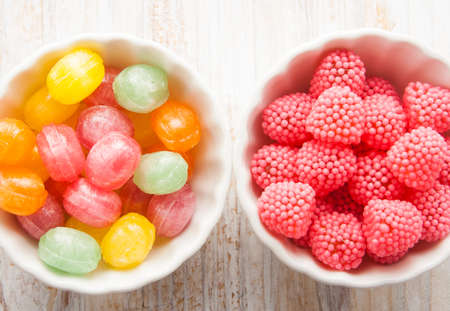 colors candies in a bowl on a wooden tableの写真素材