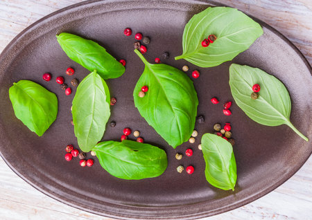 Colorful Peppercorns and Basil Leaves on dark plate. studio shotの写真素材