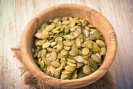 Pumpkin seeds in a wood bowl on white table. studio shotの写真素材