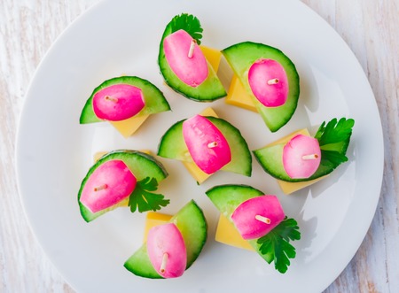 party finger foods with cheese, cucumber and radish on a wooden tableの写真素材