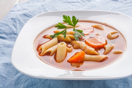 tomato soup with pasta in white plate on table. studio shotの写真素材