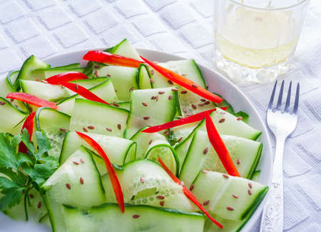 salad with cucumber, paprika and linseed on a white plateの写真素材