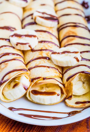 pancakes with bananas and chocolate on a white plate, studio shotの写真素材