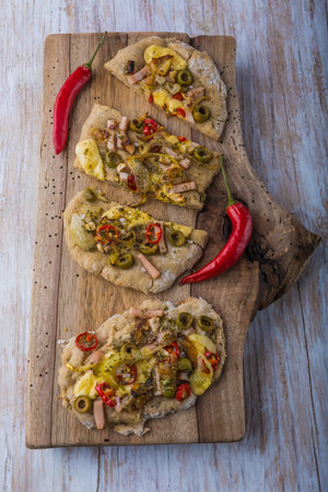 Focaccia with olives, peppers and chicken on the kitchen board