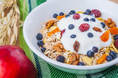 Breakfast of oatmeal with blueberries and yogurt in white bowl on wooden table