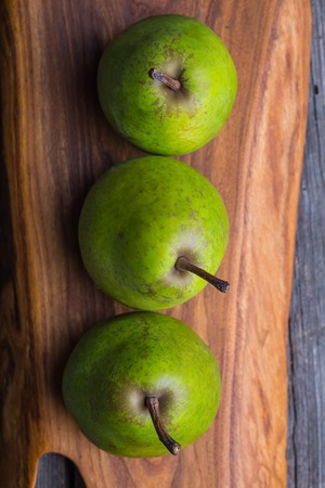 Pears on wooden cutting board and ancient wooden tableの写真素材
