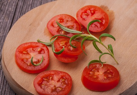 Tomato slices with rosemary on old kitchen board. studio shotの写真素材