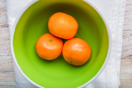 fresh tangerines in a bowl on a white wood. studio shotの写真素材