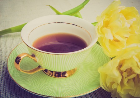 Vintage photo of cup of tea and tulips on a white tableの写真素材