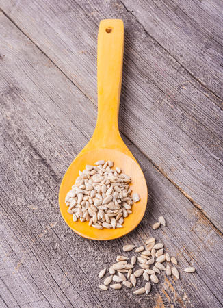 sunflower seeds on a wooden spoon on old wooden tableの写真素材