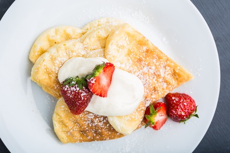Waffles with fresh strawberry and whipped cream on a white plateの写真素材