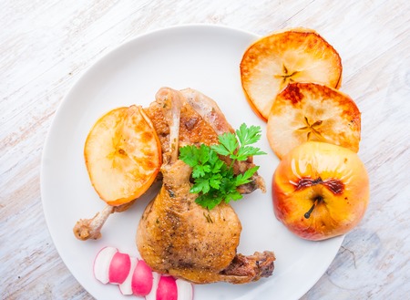 Roasted duck leg with baked apples on white plateの写真素材