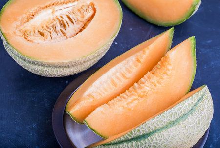 Fresh cantaloupe melon slices on a dark background