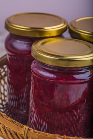 Jars of jam with fresh cherries in old basket