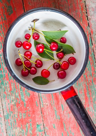 Fresh cherries in pot on old wooden table. studio shotの写真素材
