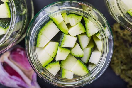 Marinated zucchini pieces in jars on black wooden tableの写真素材