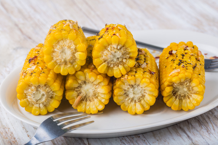 Roasted sweet corn on the cob on white plateの写真素材