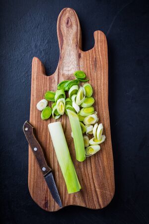 Fresh leeks whole and sliced on a wooden kitchen boardの写真素材