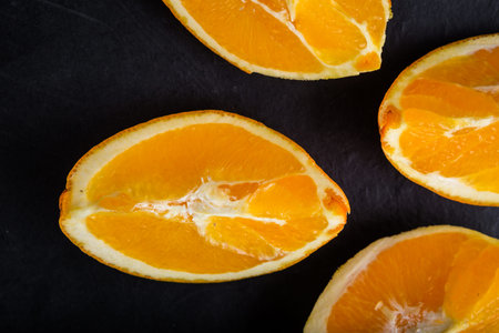 Fresh orange slices on black wooden background, studio shot