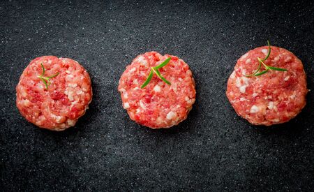 Raw burgers of beef and pork on a black boardの写真素材