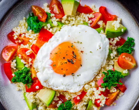 Salad with millet, avocado, cherry tomatoes and fried eggの写真素材