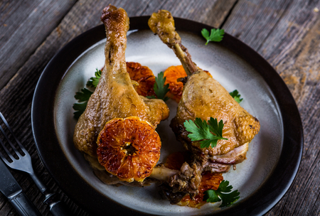 Roasted duck legs cooked in mandarins on plateの写真素材