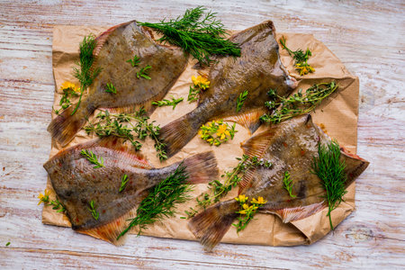 Raw fish flounder in fresh herbs on paper